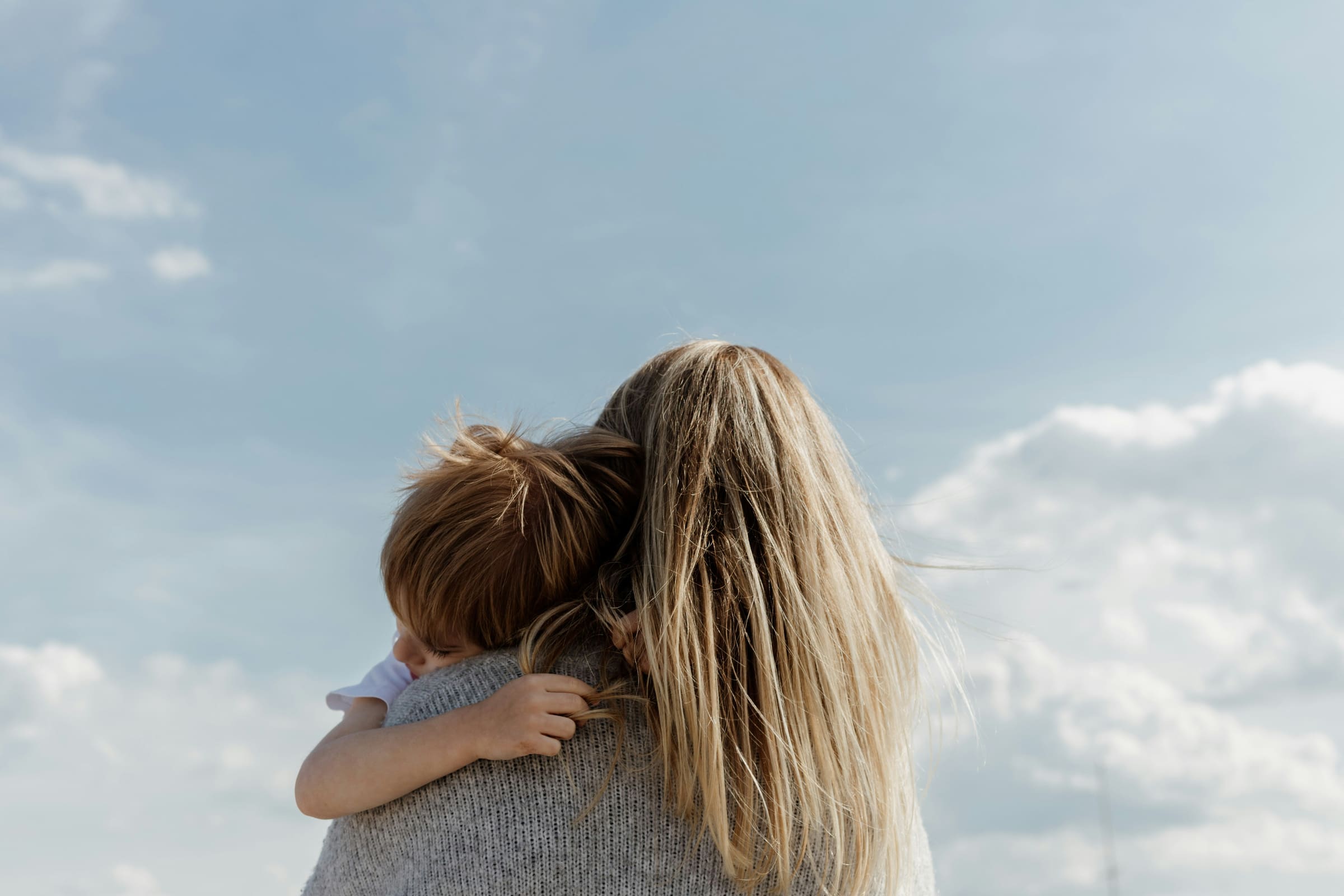 A nanny holding a child, looking out at an open sky